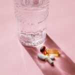 Pills next to a glass of water.